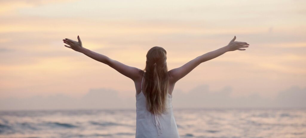 A woman enjoying a serene sunset on Unawatuna Beach, Sri Lanka, depicting peace and freedom.