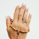 Detailed close-up of hands in prayer holding a wooden rosary with a cross.