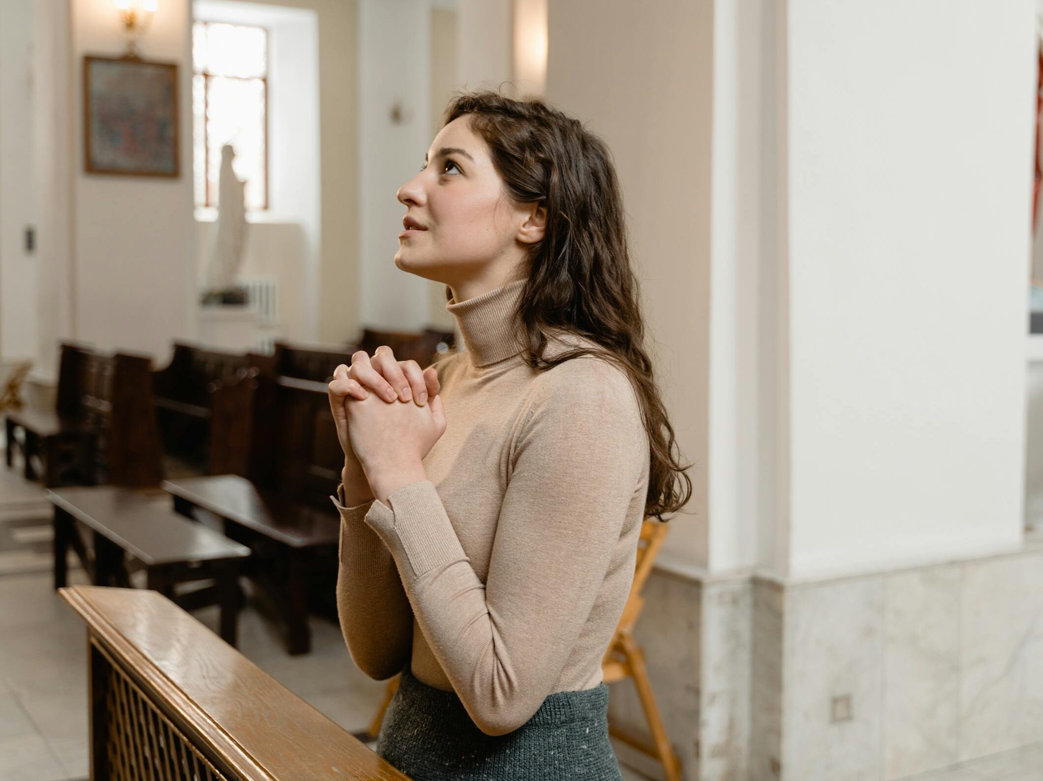 A woman deeply engaged in prayer inside a serene church setting, highlighting faith and spirituality.