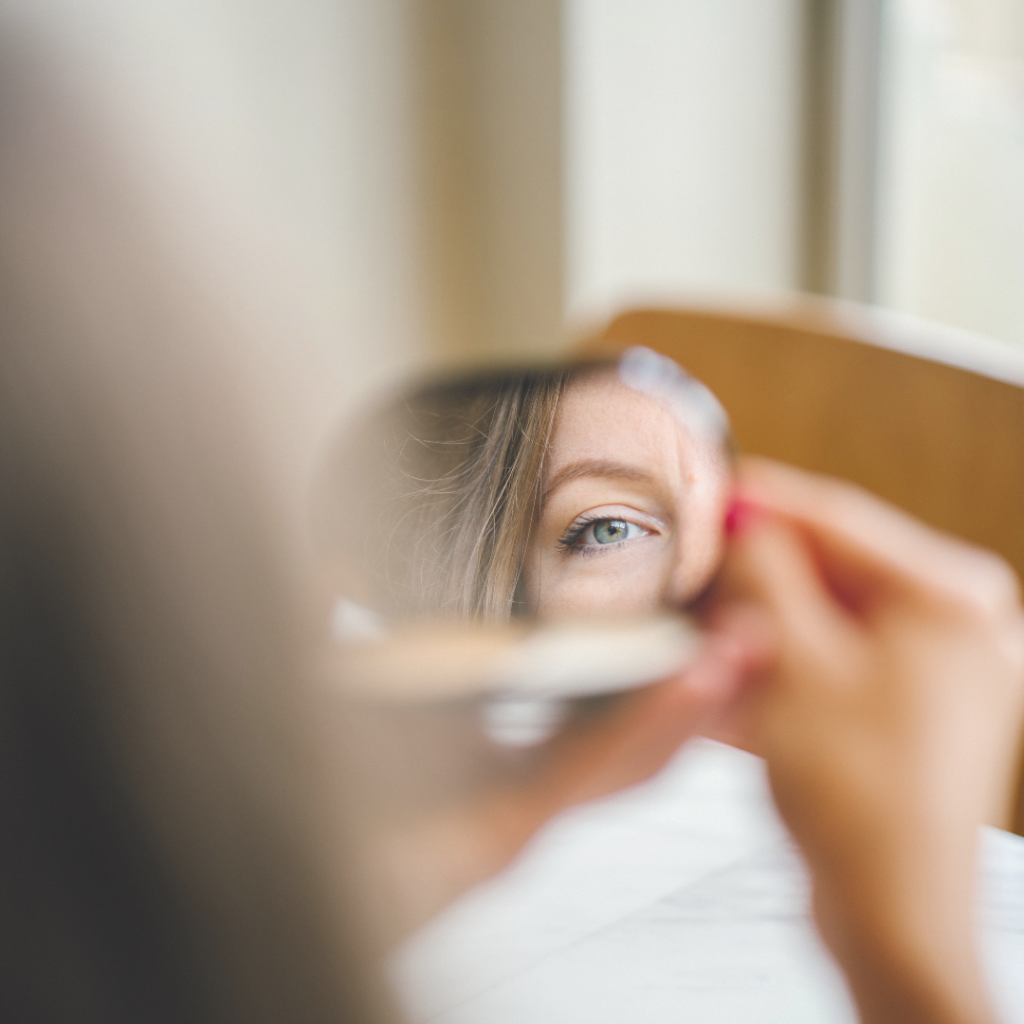 woman looking into the mirror seeing a reflection of herself.