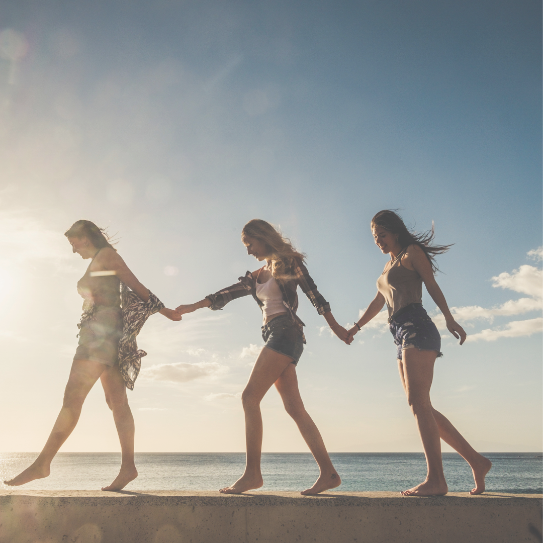 Girls walking on ledge at the pier during a beautiful sunset