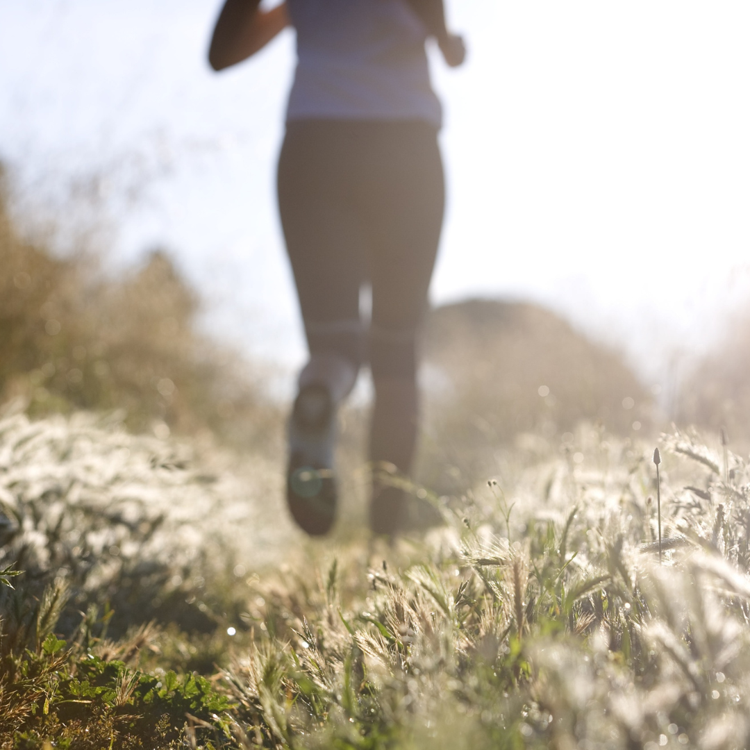 woman running on a fall day in an outdoor trail with flowers